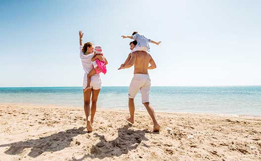 Family walking along sunny beach shoreline